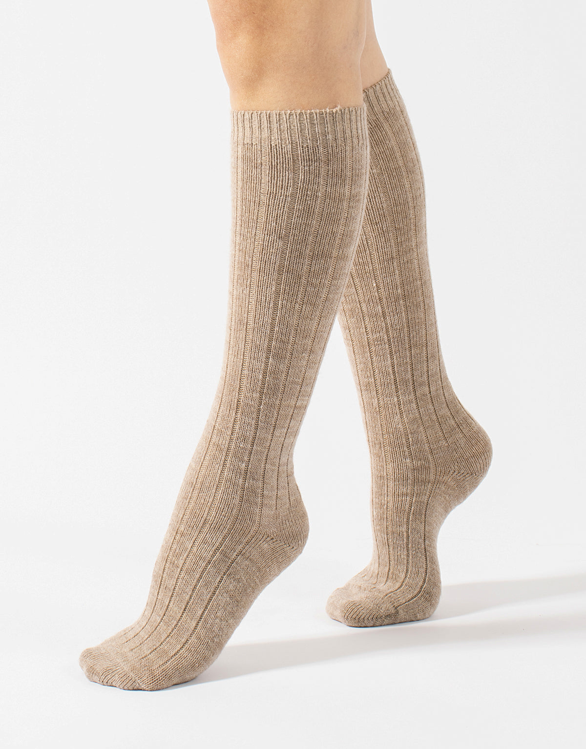 Beige knee-high socks worn by a person on a white background