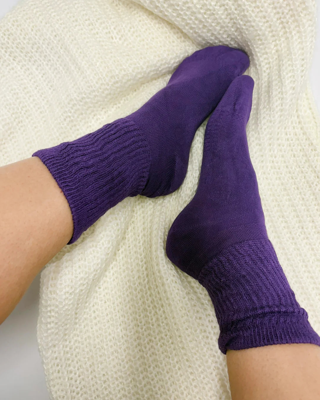 Purple socks being worn on a white background