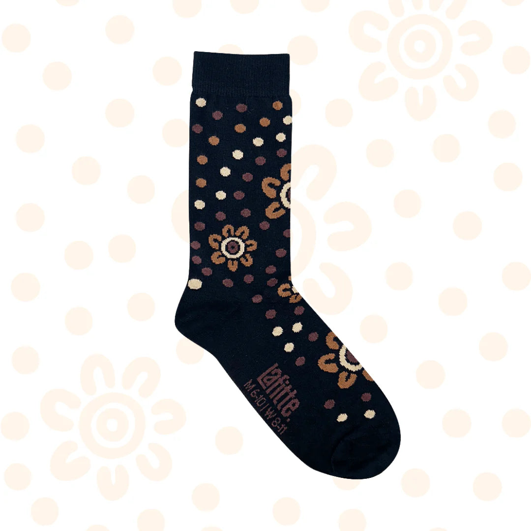 Black sock with an aboriginal design pattern on a beige background