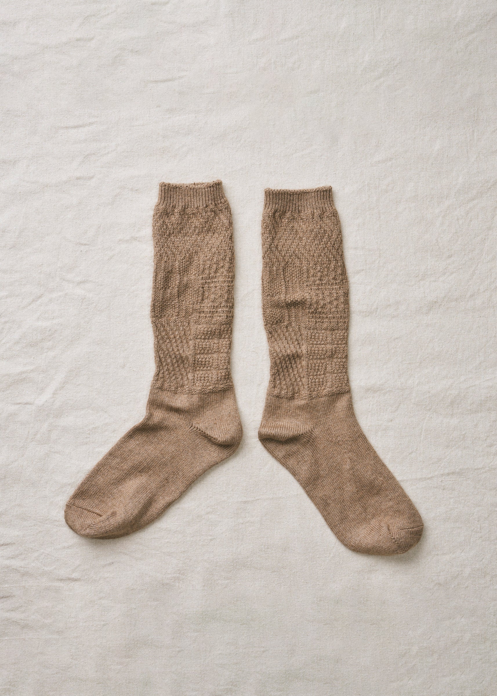 Pair of brown knee-high socks on a textured beige background