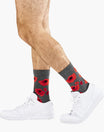 Gray socks with red poppy patterns worn with white sneakers on a white background