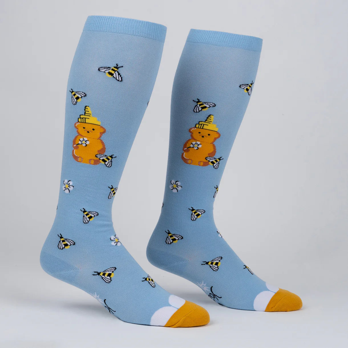 Light blue socks with honey bear and bee design on a white background