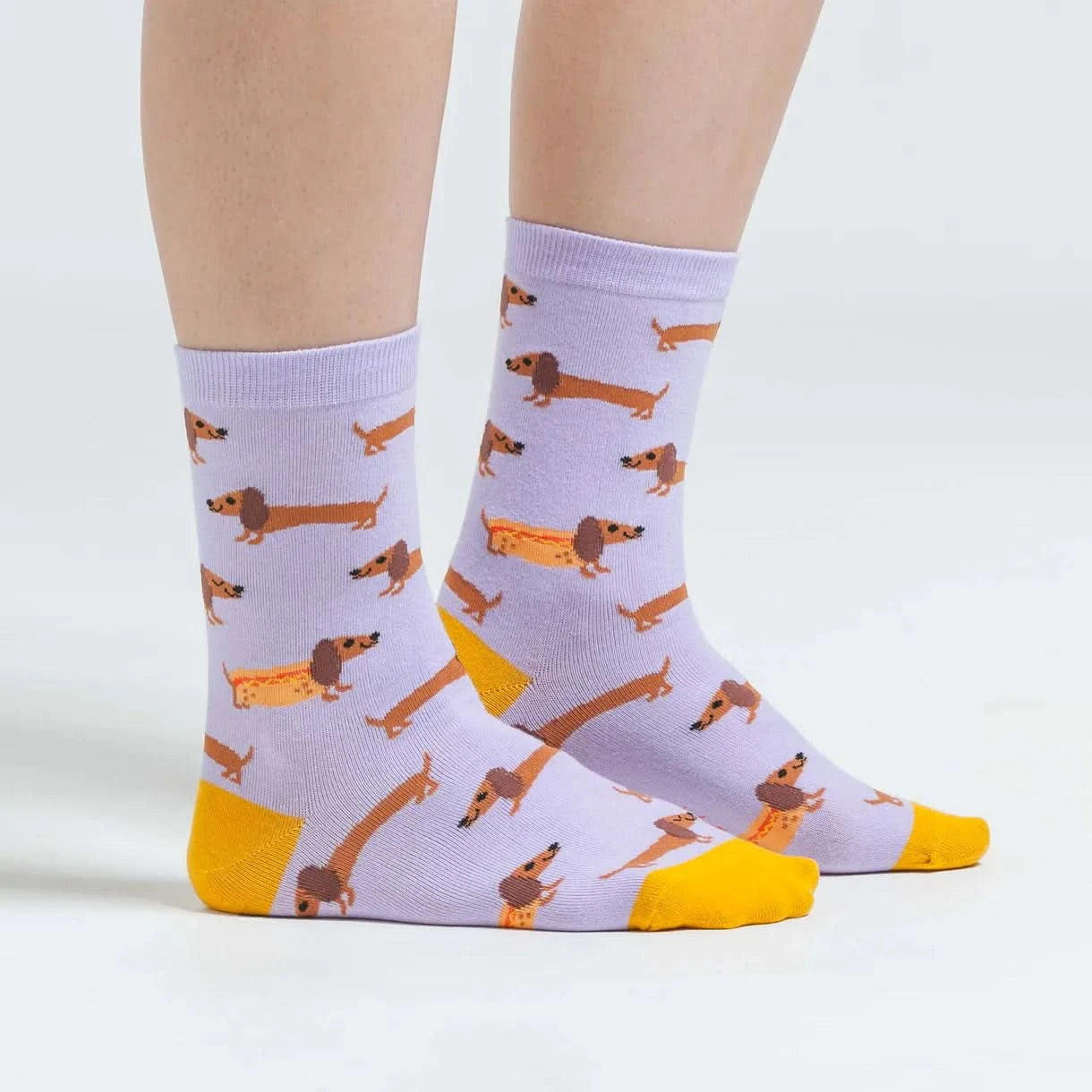 lilac coloured womens novelty crew sock with sausage dogs some in a hot dog bun, heel and toe yellow