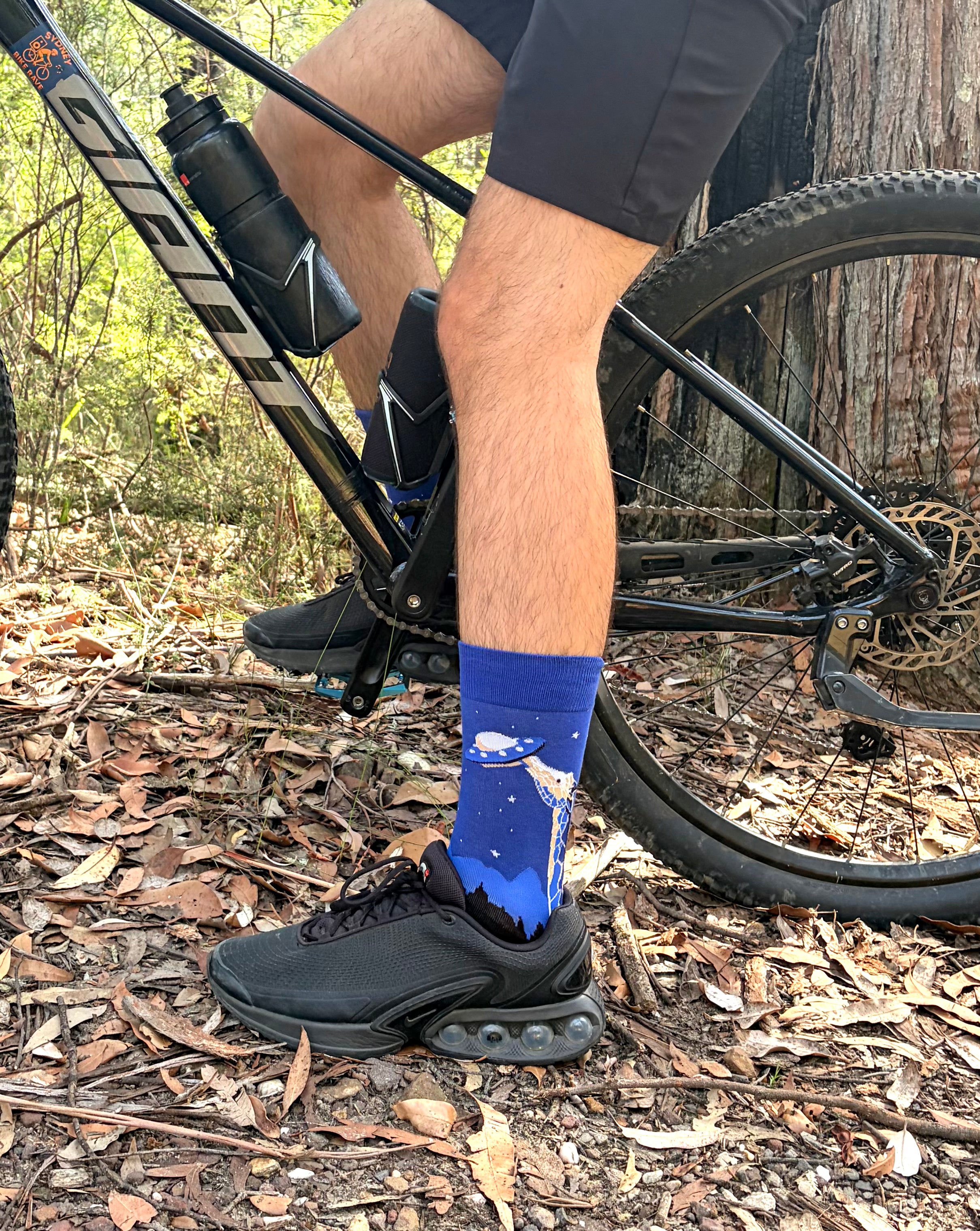 Person wearing blue cycling socks with a mountain bike in a forest setting