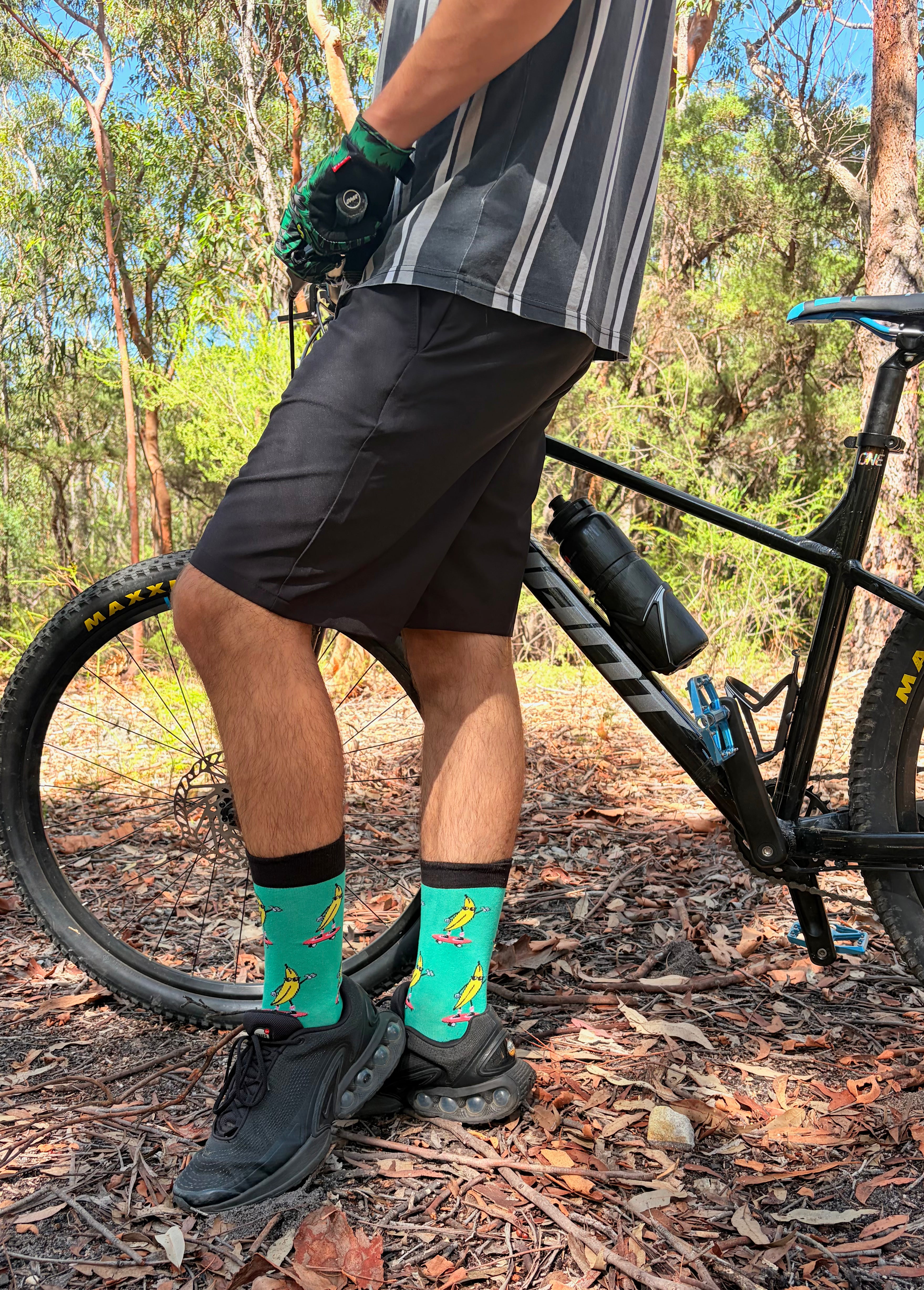 Person wearing colorful peeling out novelty socks with a bicycle in a bush setting