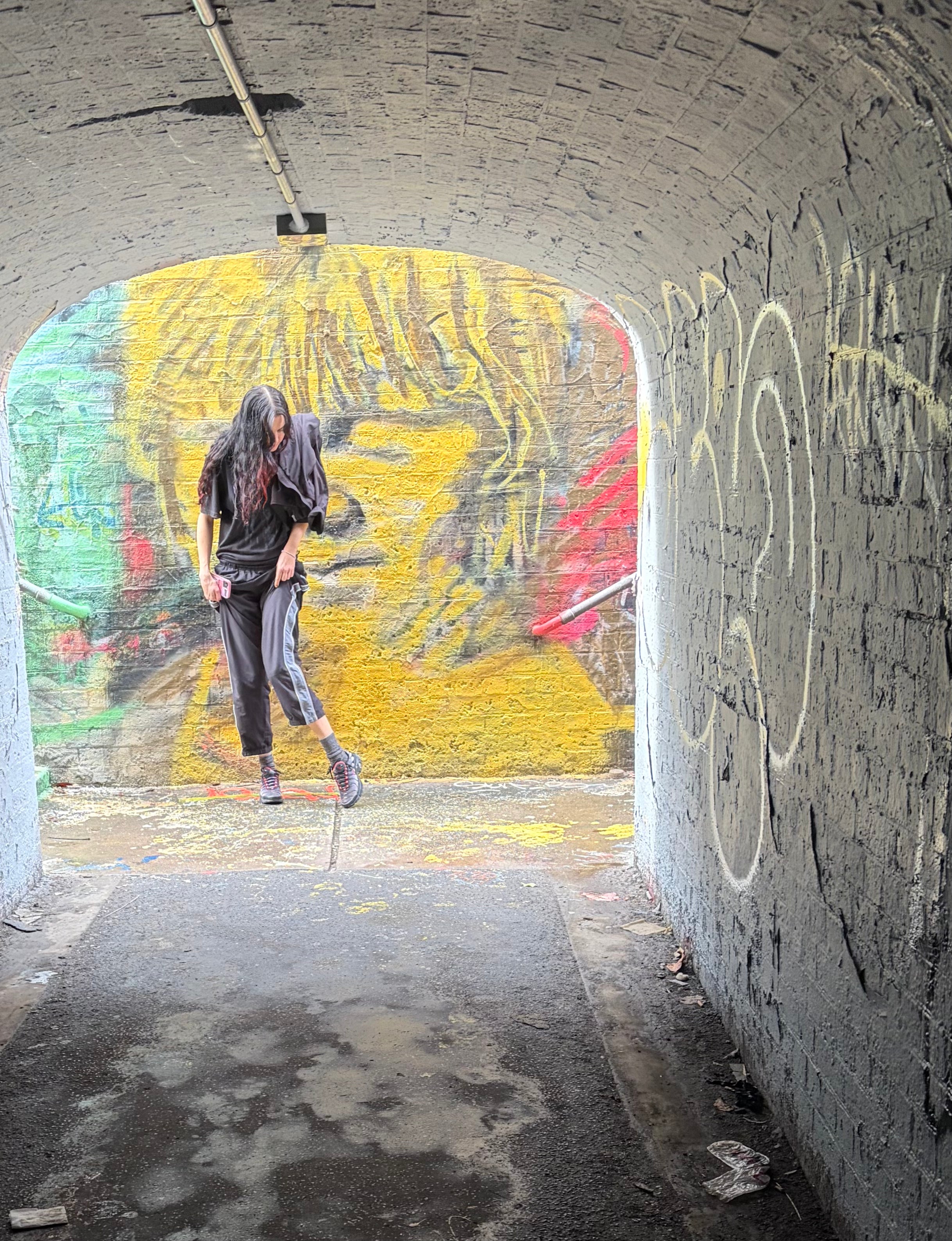 Person standing in a tunnel with colorful graffiti on the walls