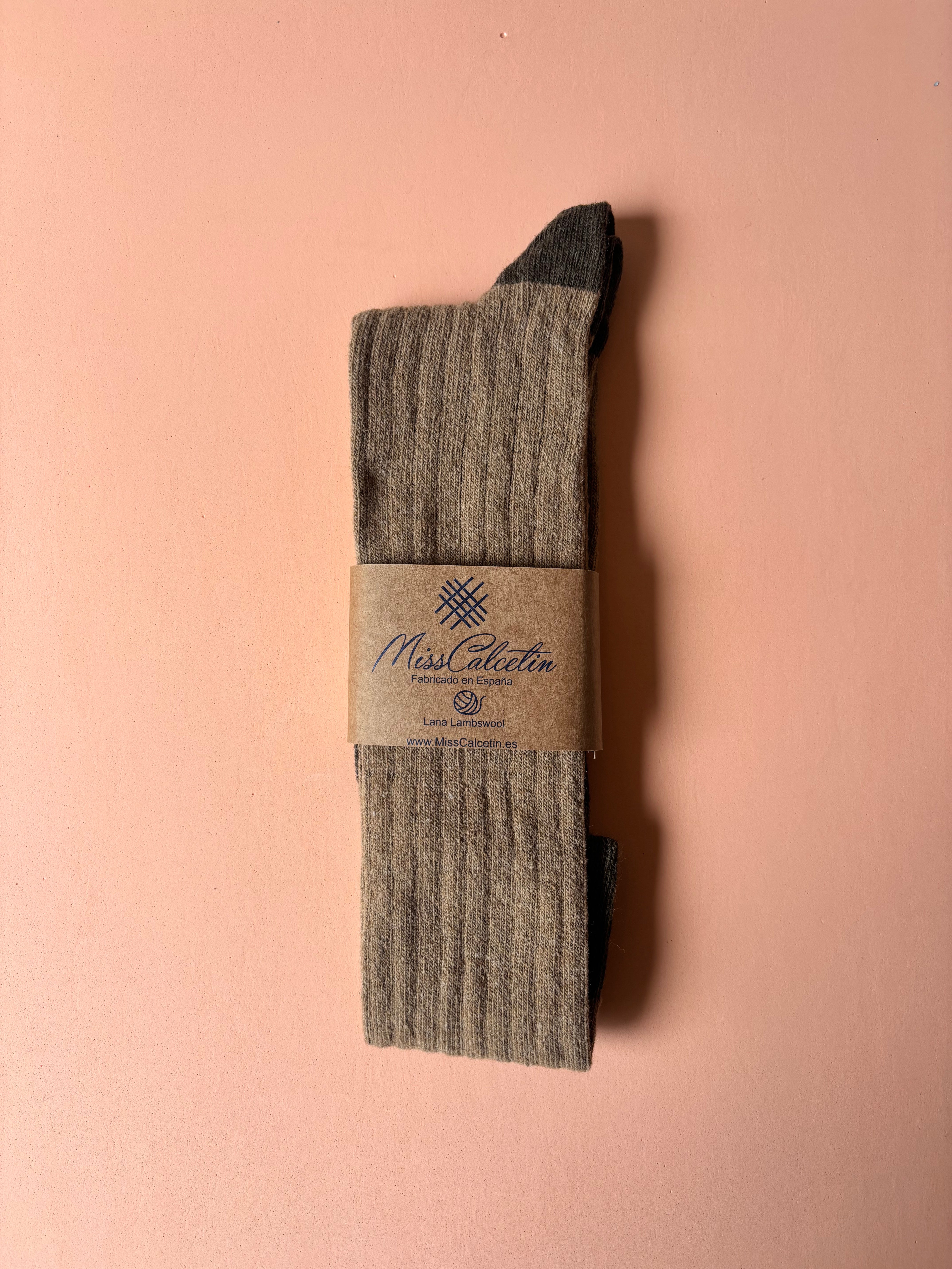 Pair of brown socks with a label on a pink background