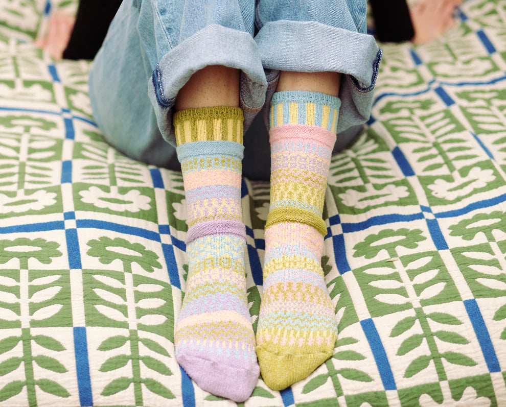 Pastel striped socks worn on a patterned blanket
