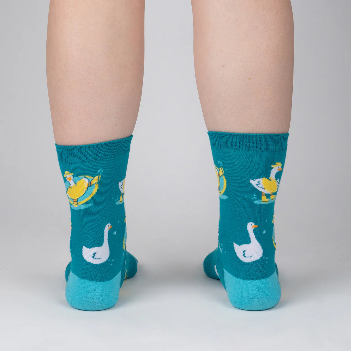 Teal socks with duck and swan designs worn by a person on a light gray background