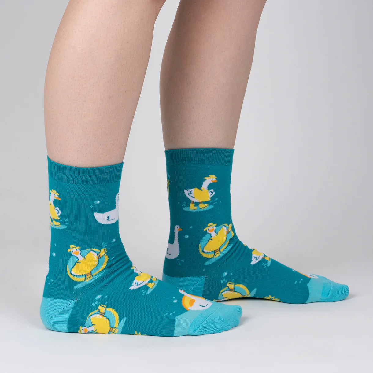 Teal socks with duck pattern worn by a person on a light gray background