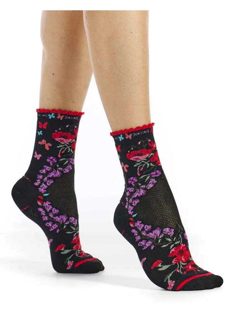Black socks with floral patterns worn by a person on a white background