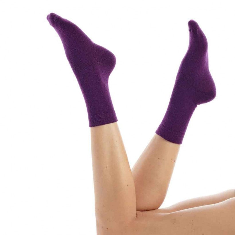 Purple socks worn by a person on a white background
