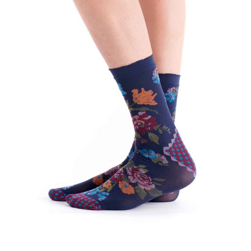 A pair of navy blue crew socks with a colorful floral and geometric pattern, worn on a person's feet against a plain white background.