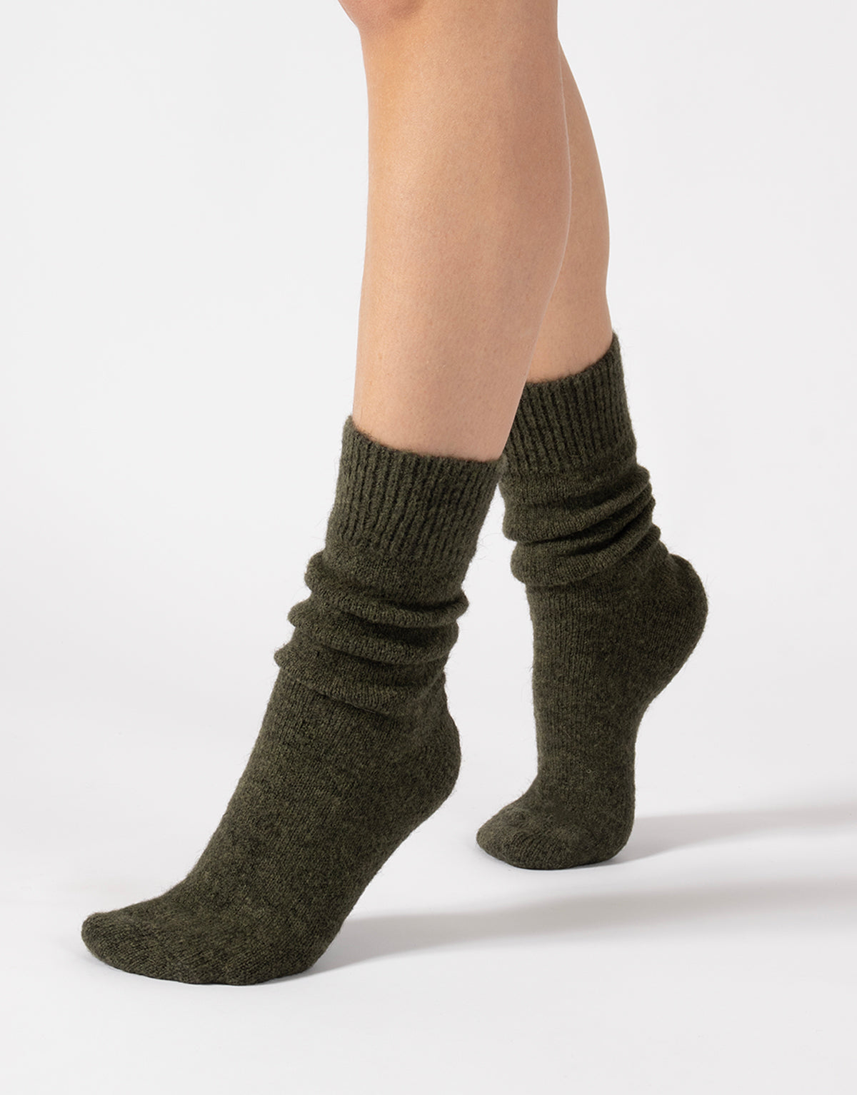 Dark green socks worn by a person on a light gray background