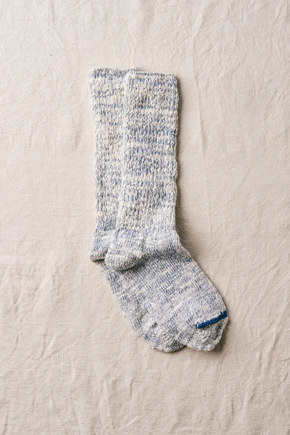 Pair of indigo socks on a beige fabric background
