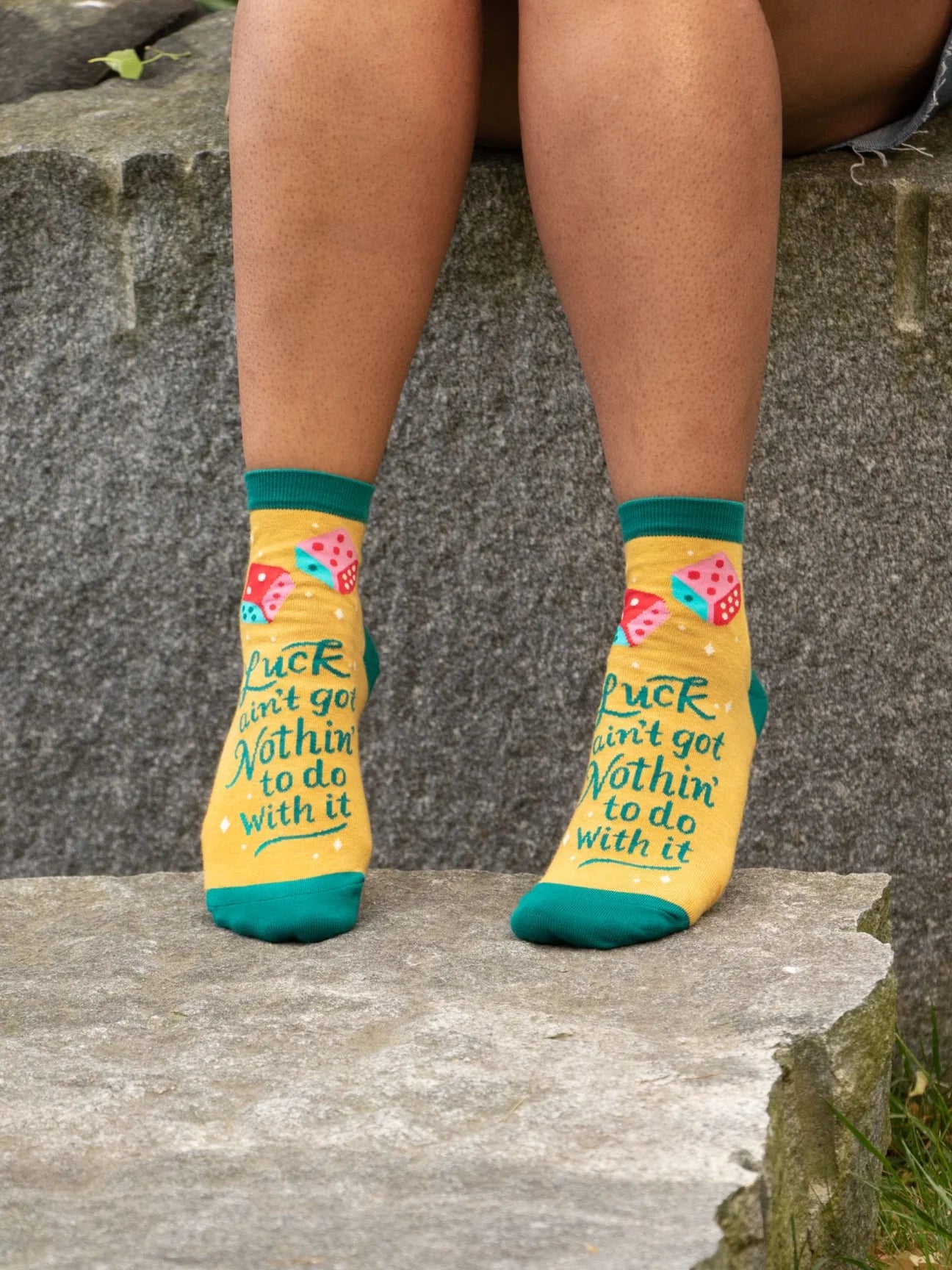 Person wearing mustard socks with design with dice and text, standing on stone steps.
