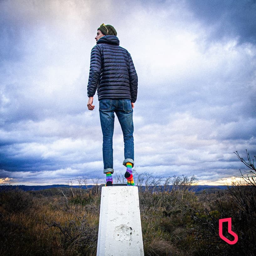 Man standing looking at the view wearing warm clothes and rainbow socks
