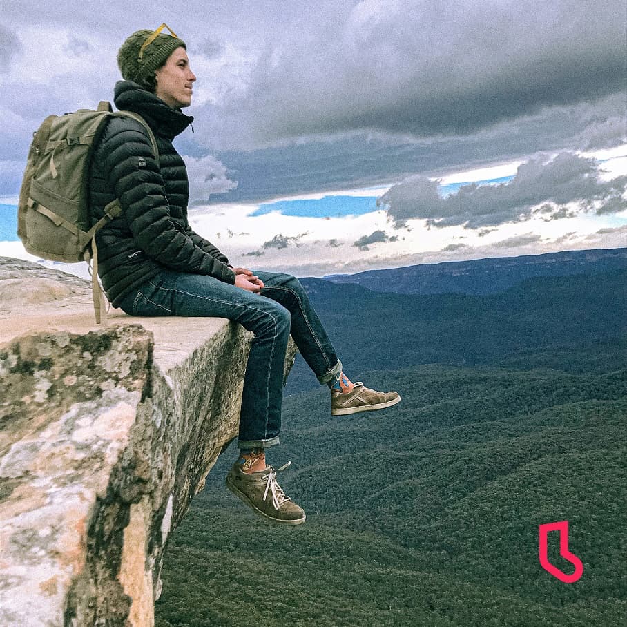 man sitting on the edge of a cliff wearing a pair of squid o men novelty sock