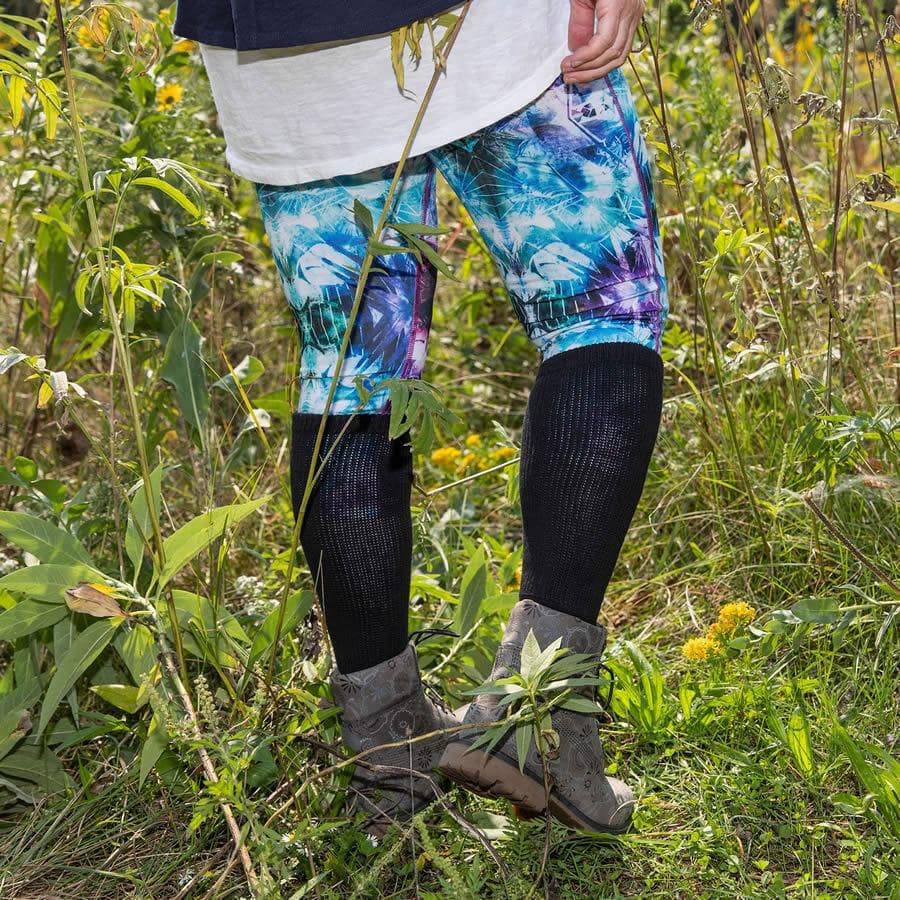 Woman waring black loose fit over the calf socks over colourful leggings - The Sockery