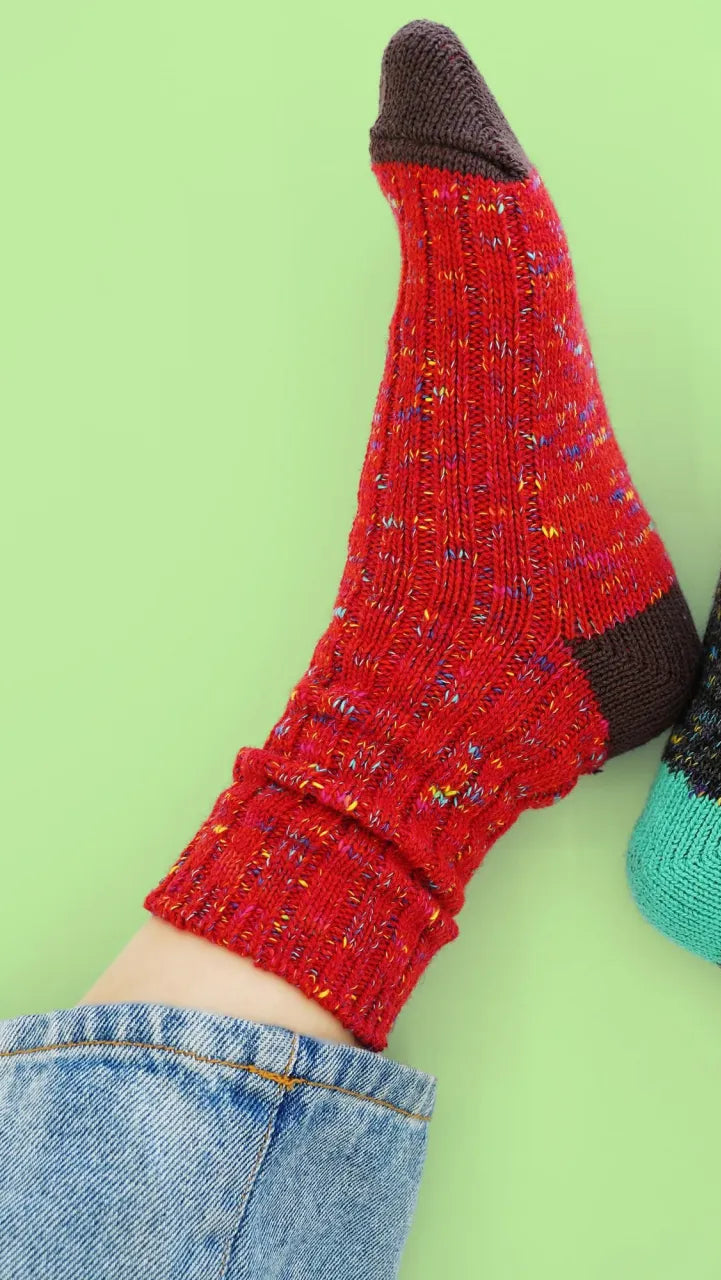 Red and black socks with a blue toe on a green background