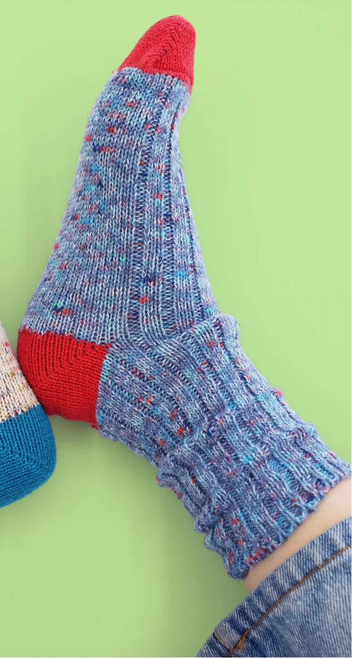 Colorful knitted socks with blue and red accents on a green background
