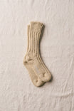 Pair of beige knitted socks on a textured beige surface