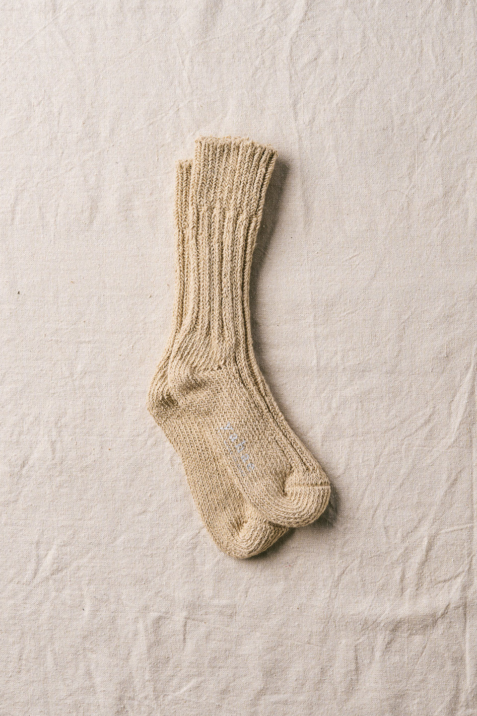 Pair of beige knitted socks on a textured beige surface