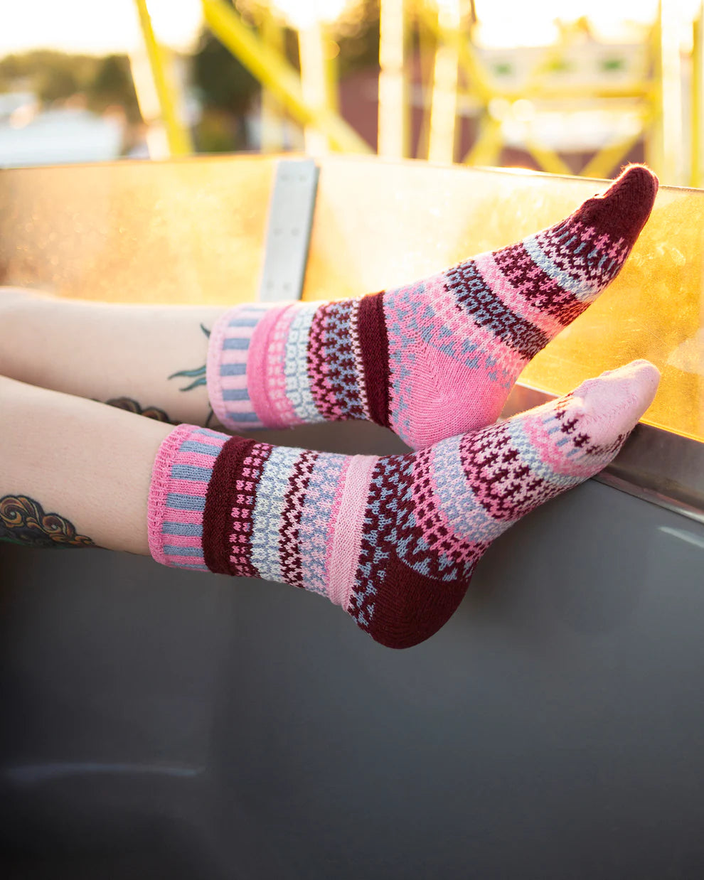 Colorful patterned socks on a person's feet with a blurred outdoor background
