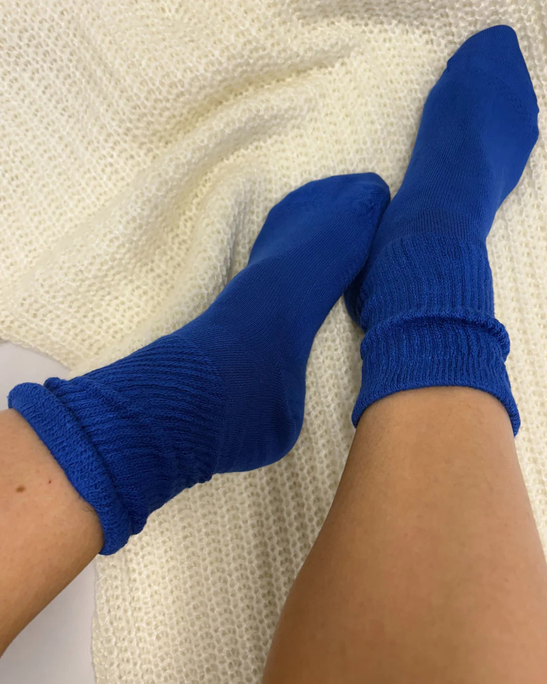 Blue socks being worn on a textured white surface