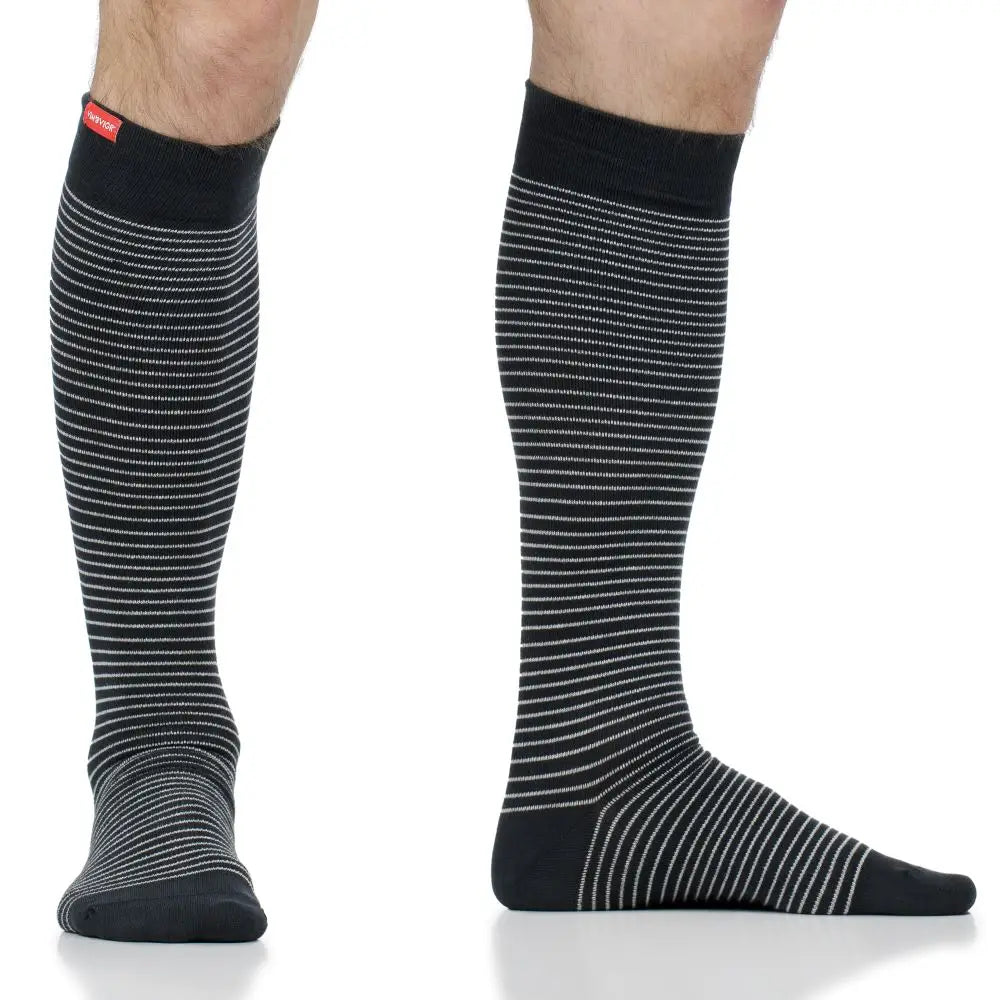 Black knee-high compression socks with white stripes worn by a person on a white background