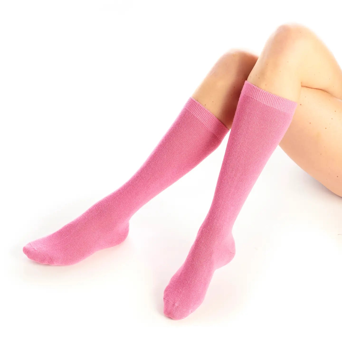 Pink knee-high socks worn by a person on a white background