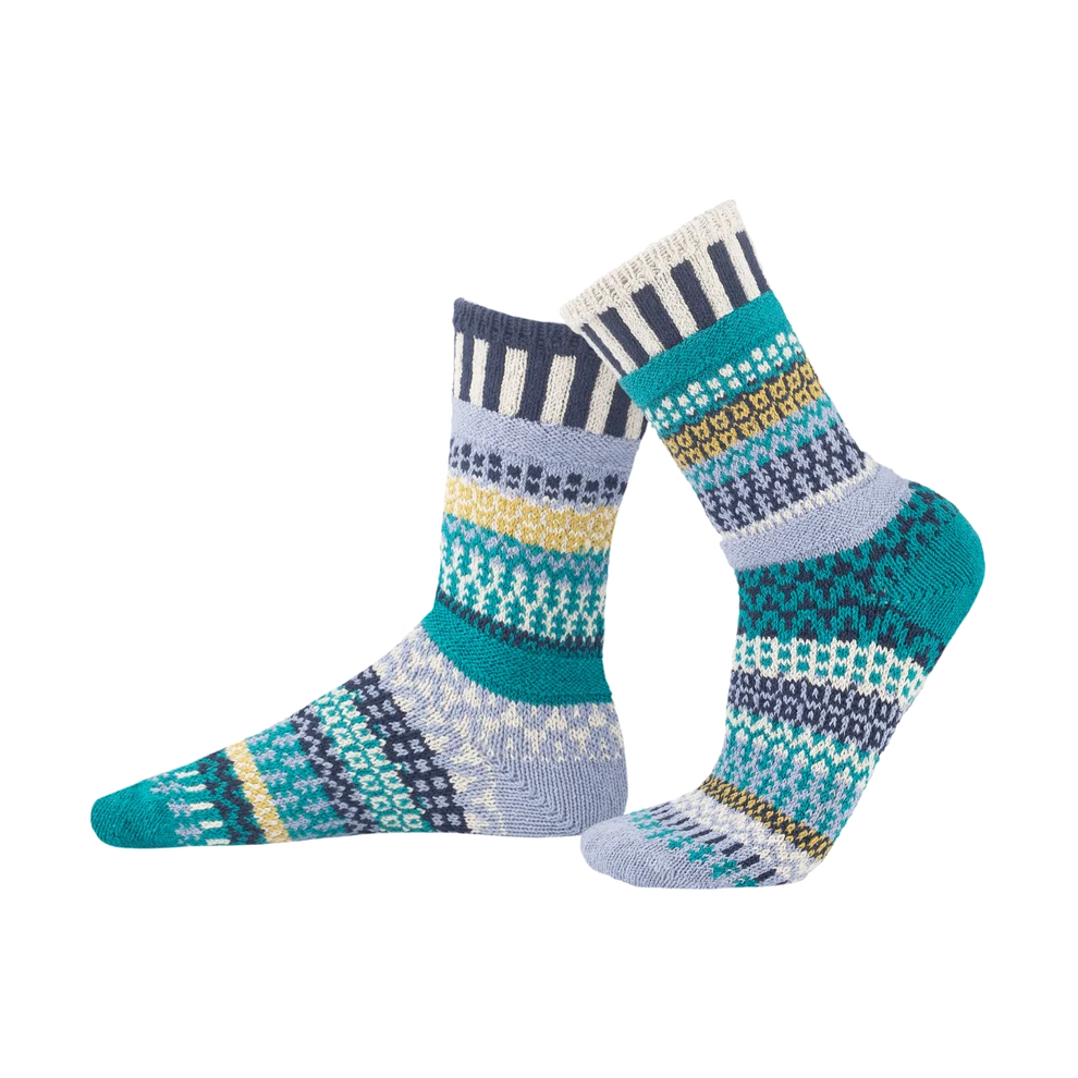 A pair of crew socks with a multicolor  pattern in teal, navy, light blue, yellow, and white, shown against a plain white background.