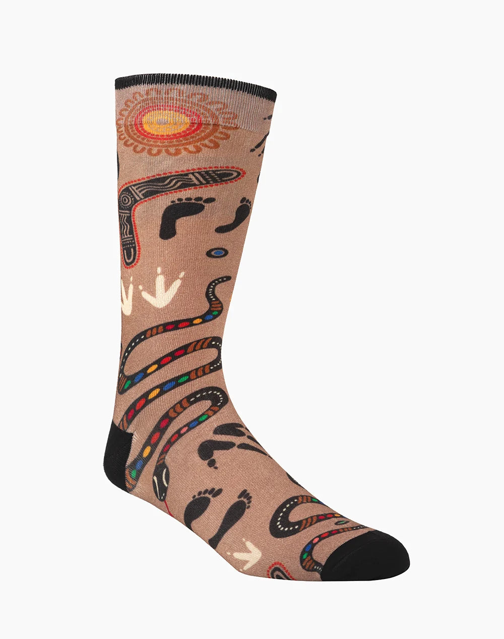 A single crew sock with a tan background featuring a stylized Aboriginal-inspired design with black footprints, red and yellow sun motifs, and multicolored snake patterns, shown on a light gray background.