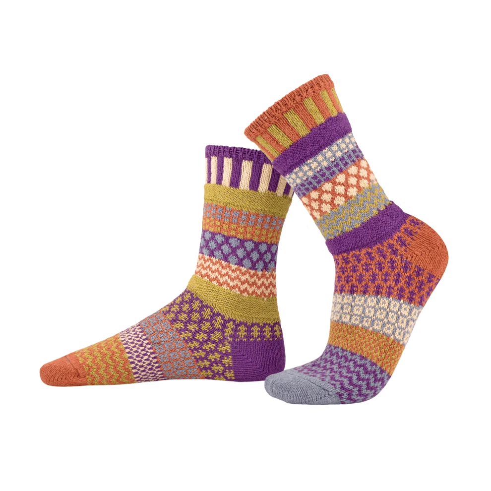 A pair of crew socks with a colorful geometric pattern in purple, orange, yellow, and cream, displayed against a plain white background.