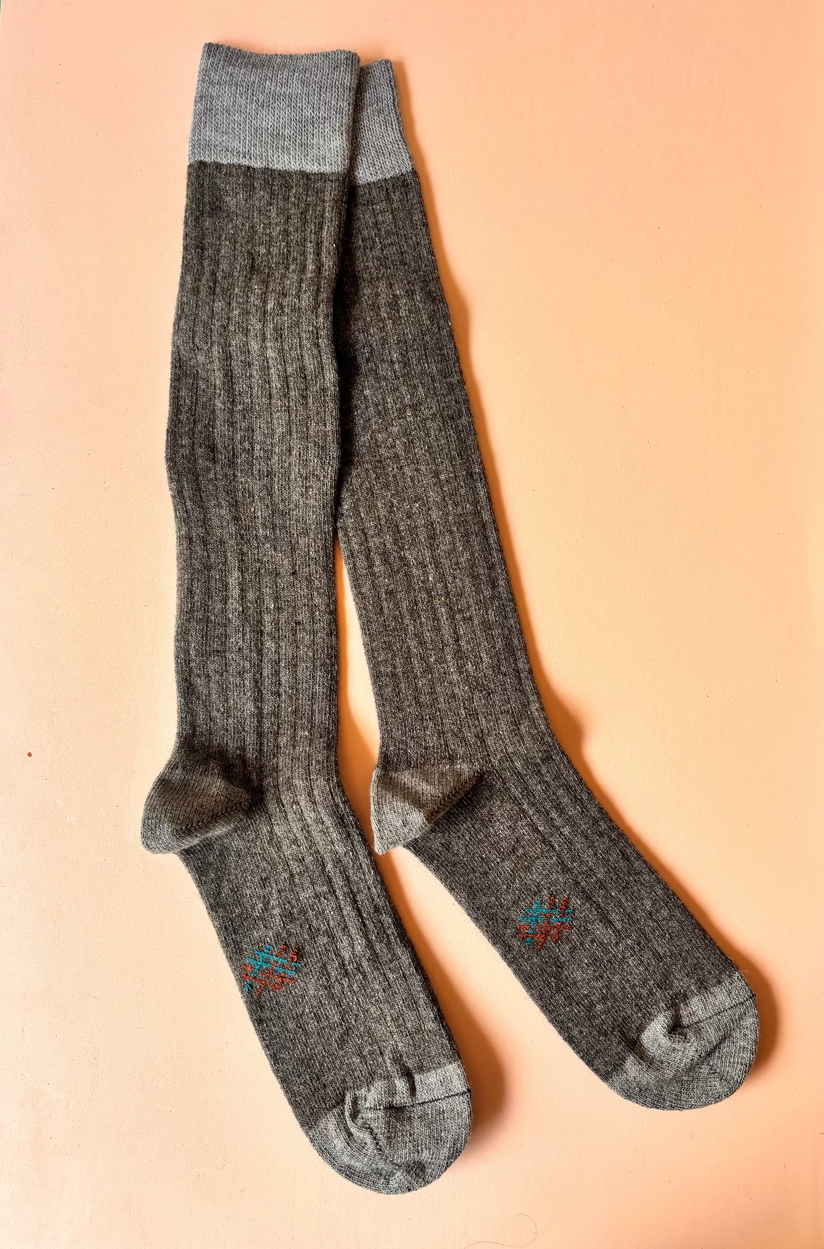 Pair of gray knee-high socks on a peach background