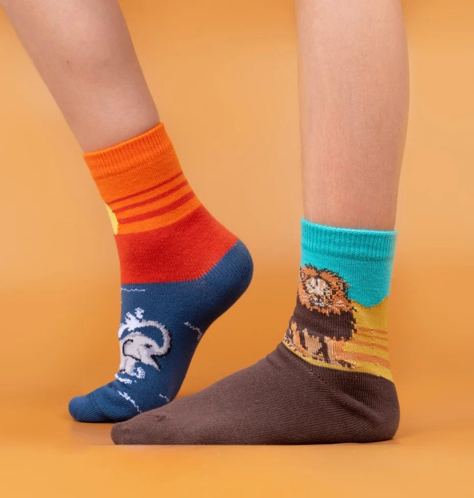 Three pairs of feet wearing colorful socks with various designs on a multicolored background.