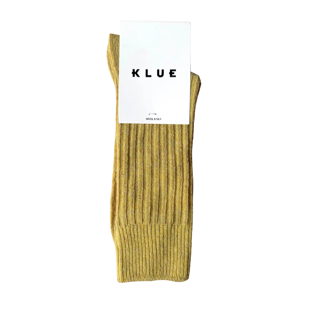 Mustard yellow sock with KLUE label on a white background