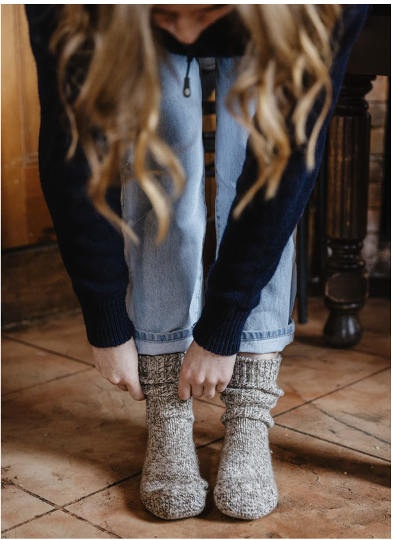 Person wearing knitted socks on a wooden floor