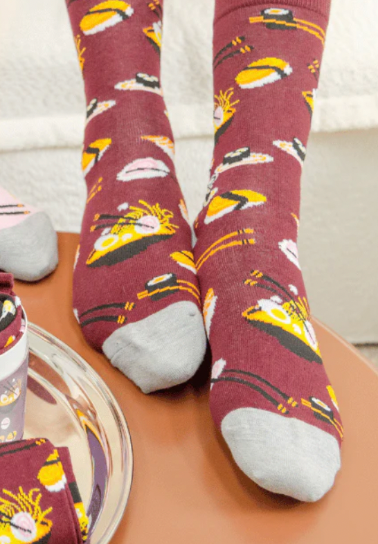 Maroon socks with sushi pattern worn on a wooden surface