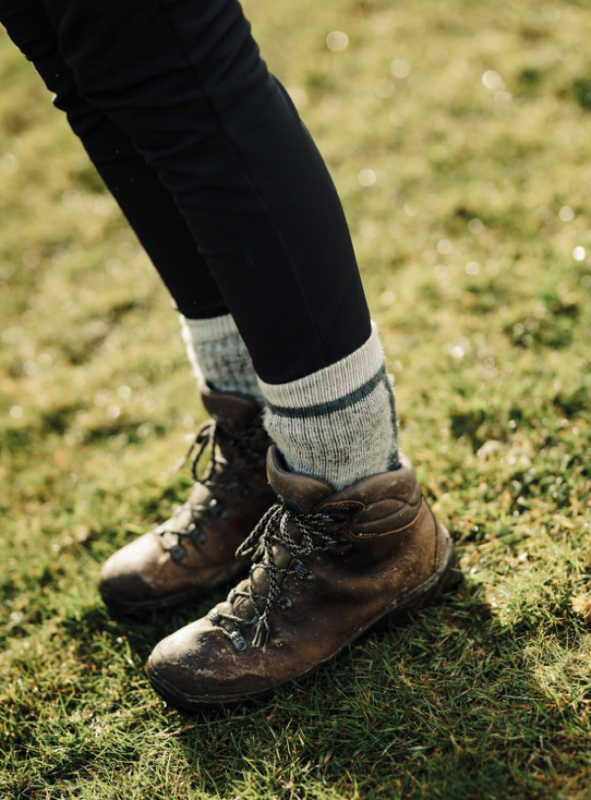 Brown hiking boots on a person standing on grass