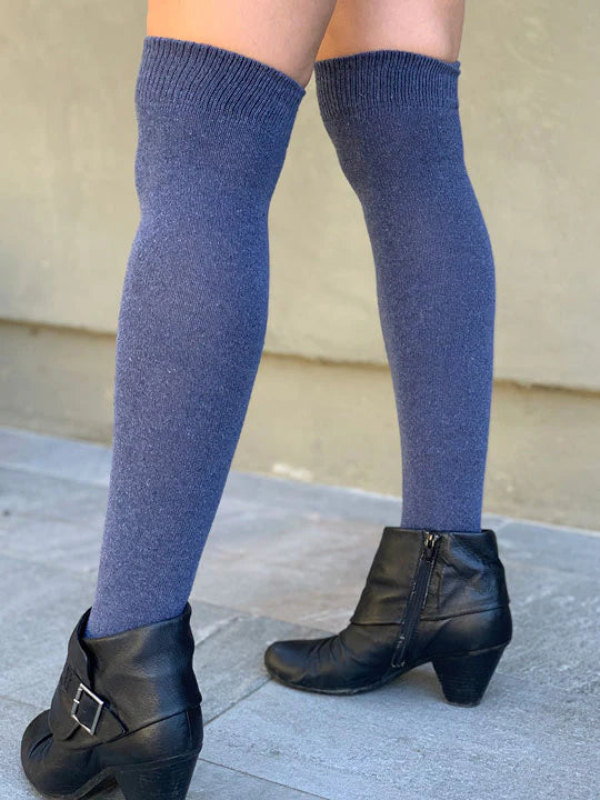 Person wearing blue over the knee-high socks and black boots on a neutral background
