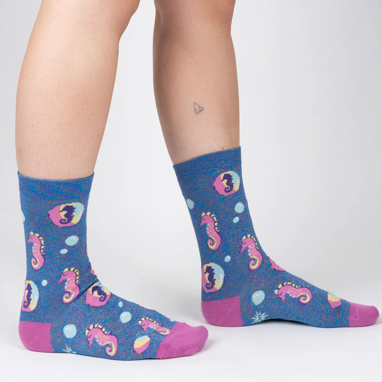 Person wearing blue socks with pink seahorse designs on a white background