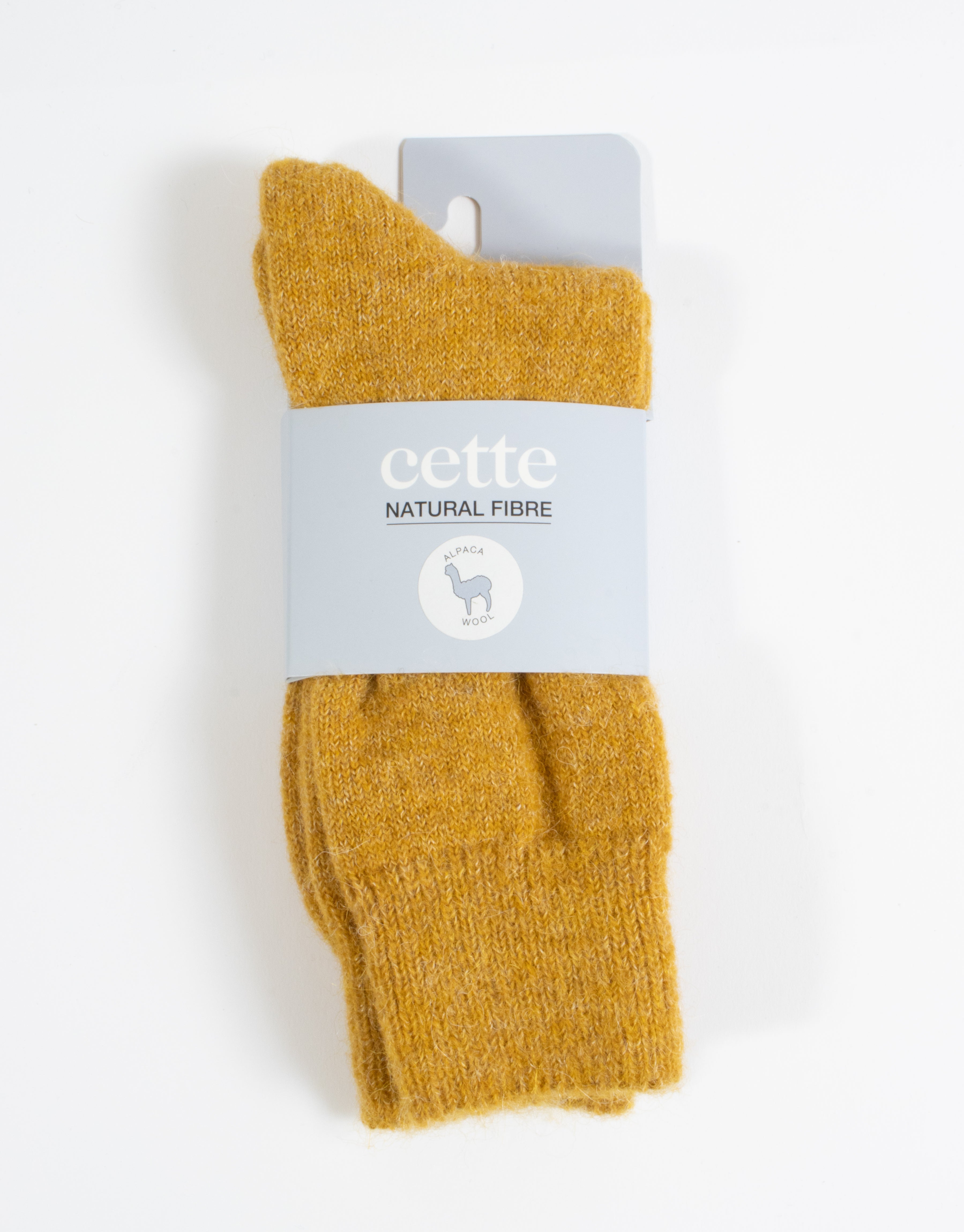 Mustard yellow sock with 'cette' label on a white background