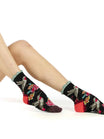 Person wearing black socks with floral and humming bird designs on a white background