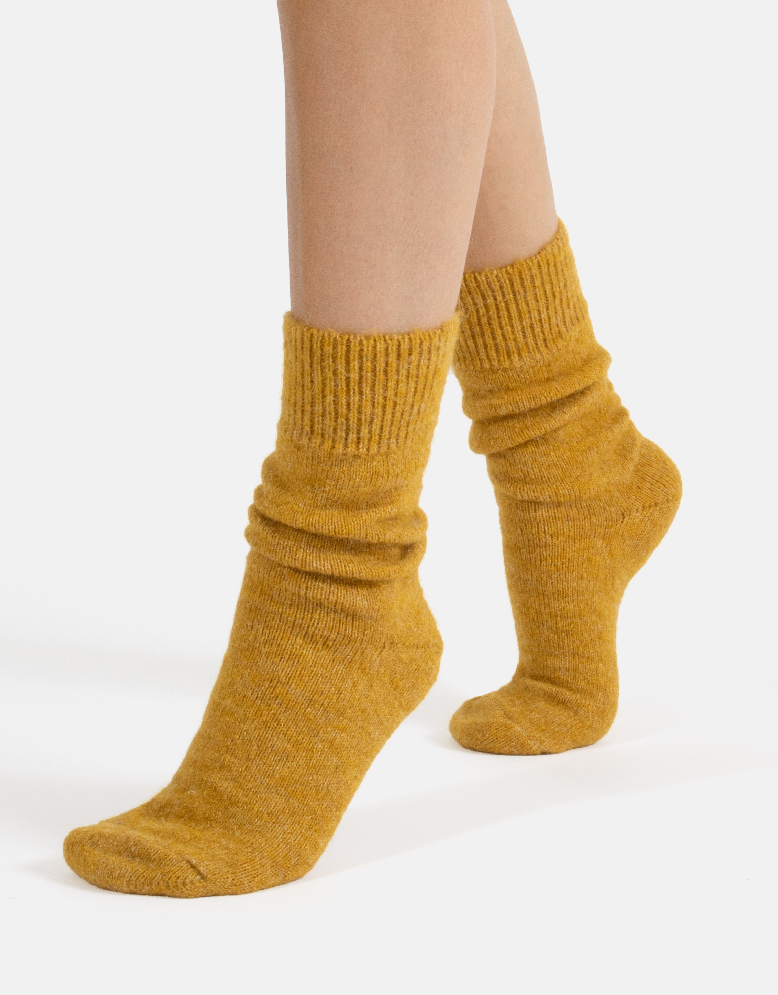Mustard yellow socks worn by a person on a white background