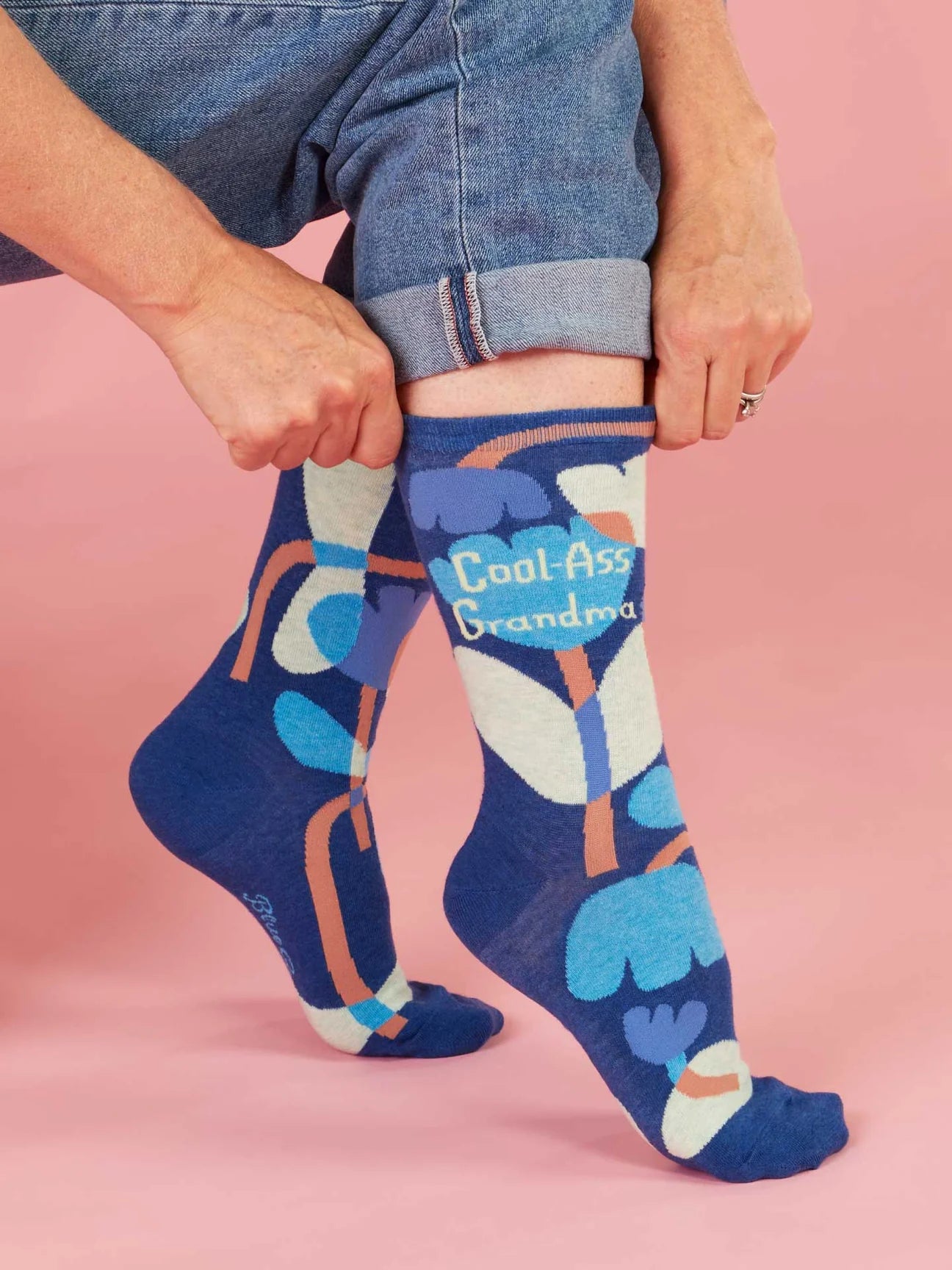 Person wearing blue socks with colourful designs and text 