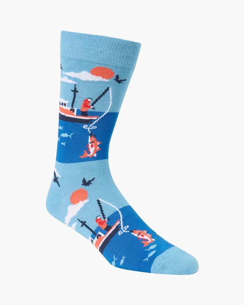 A single crew sock with a colorful nautical pattern featuring a fishing boat, fish, birds, and a sun on a light blue and dark blue background, shown on a plain light gray studio background.
