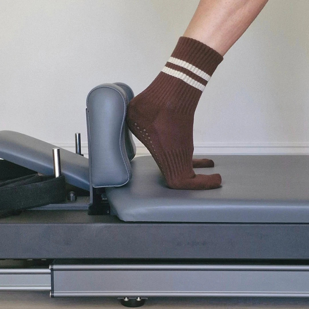 Person wearing brown socks with white stripes on a treadmill.