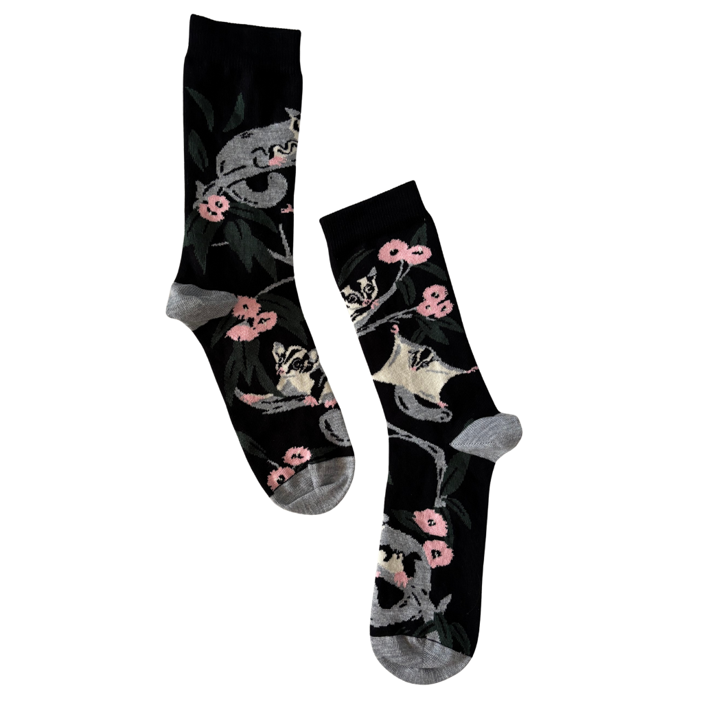 Two socks with possum and floral design on a black background