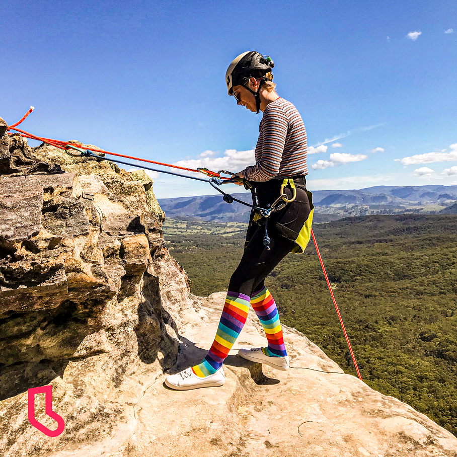 woman rock climbing in rainbow coloured socks